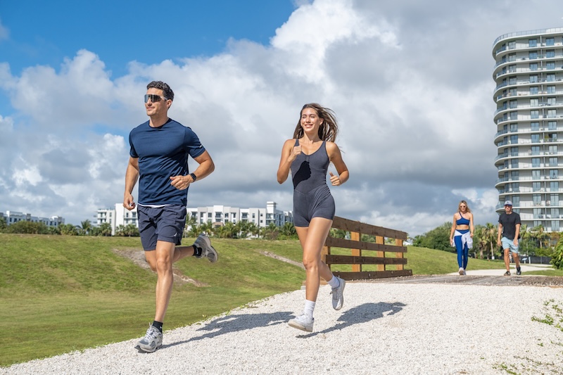 people running on a trail with a building behind them