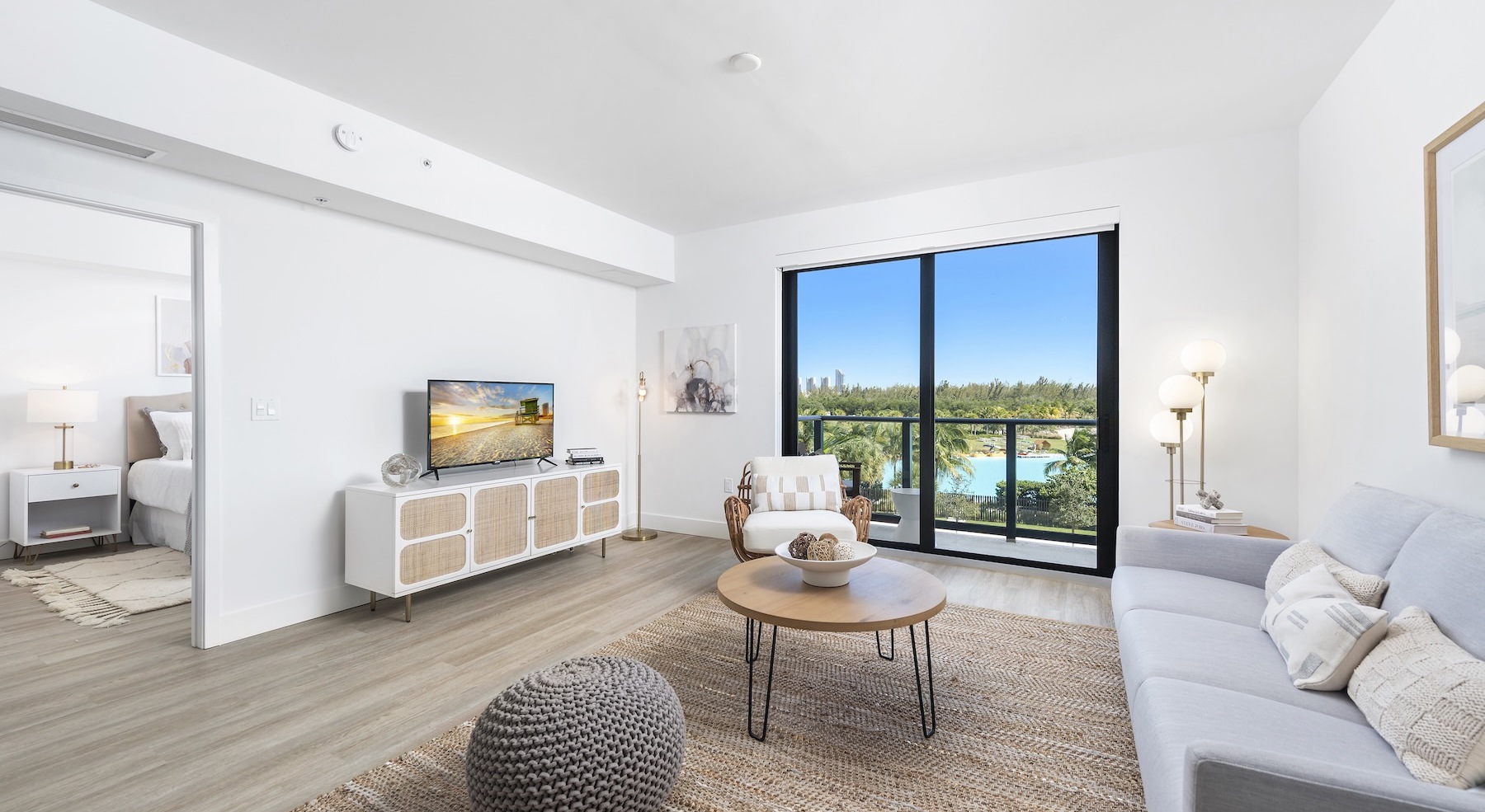 living area with a tv, couch and coffee table next to a large window