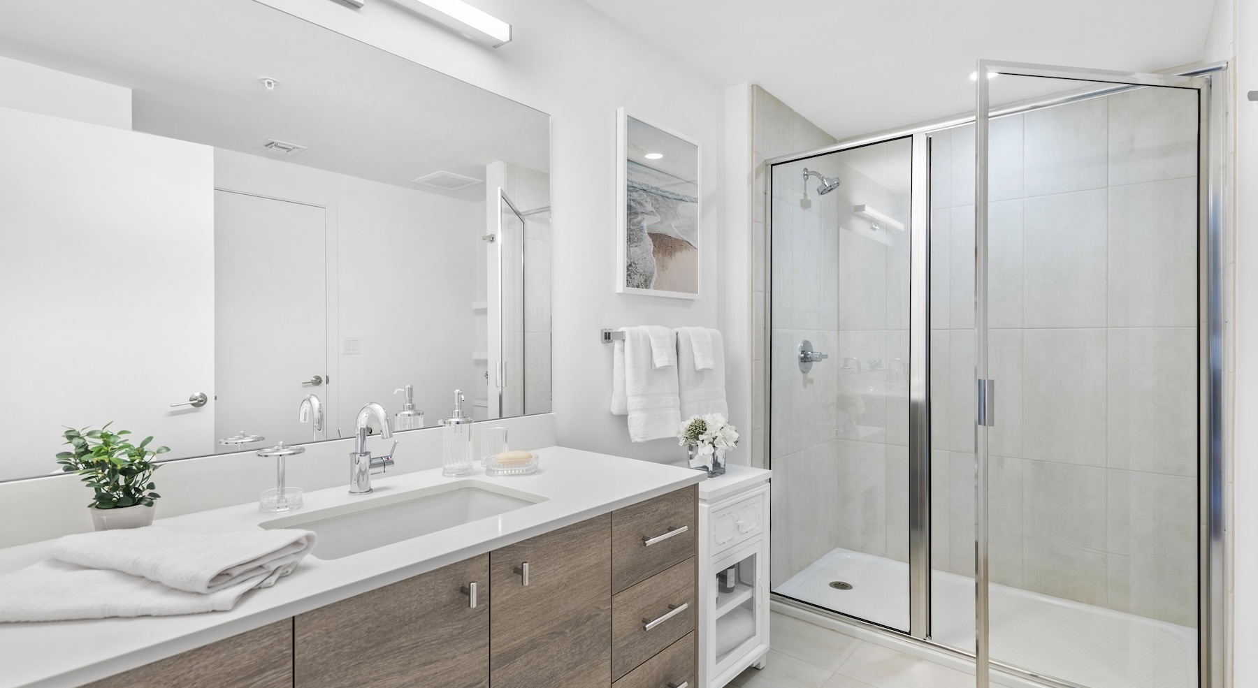bathroom with a large mirror and walk-in shower