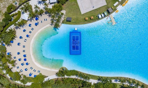 birds eye view of blue waters with sandy beach and floating blue pickleball court