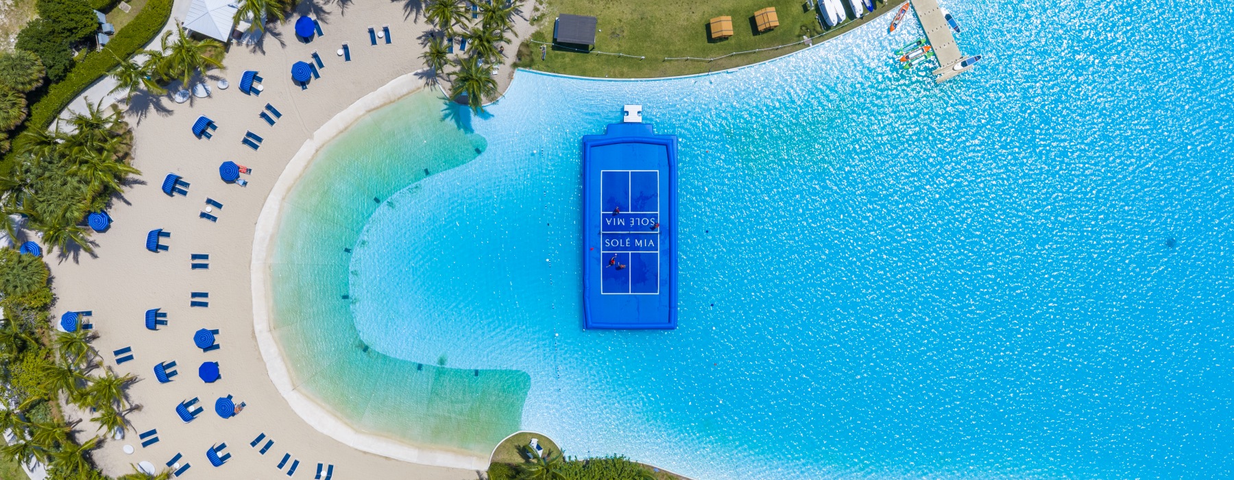 birds eye view of blue waters with sandy beach and floating blue pickleball court