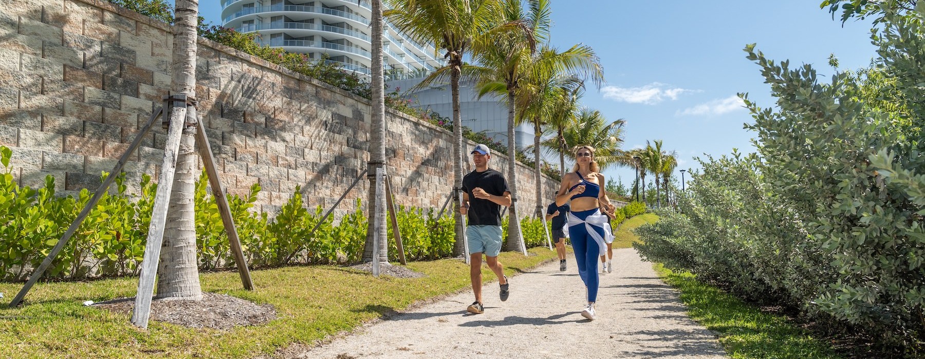 people running on a gravel path between trees