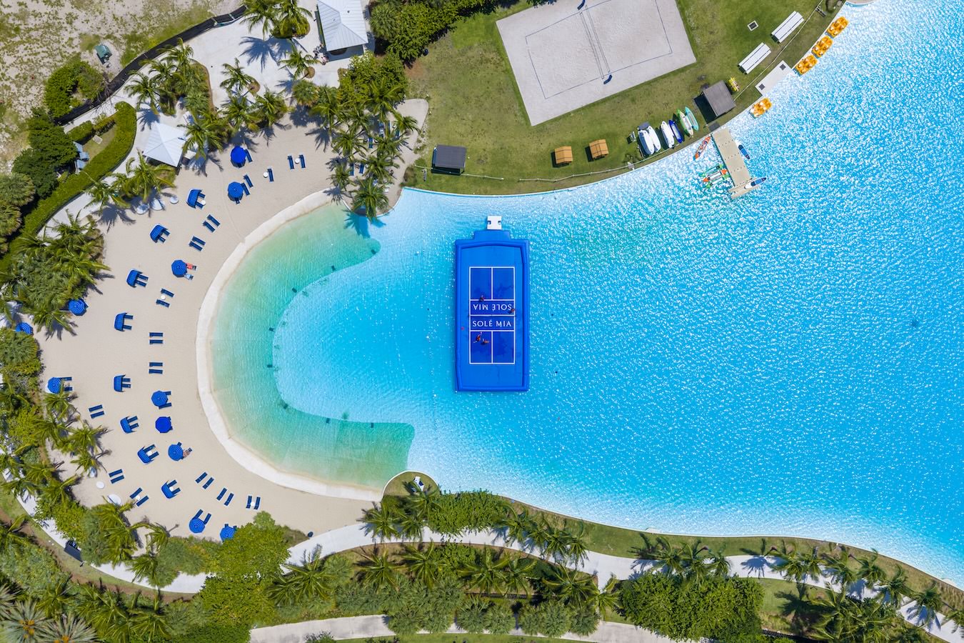 aerial view of a pool with a floating pickleball court and sand volleyball court